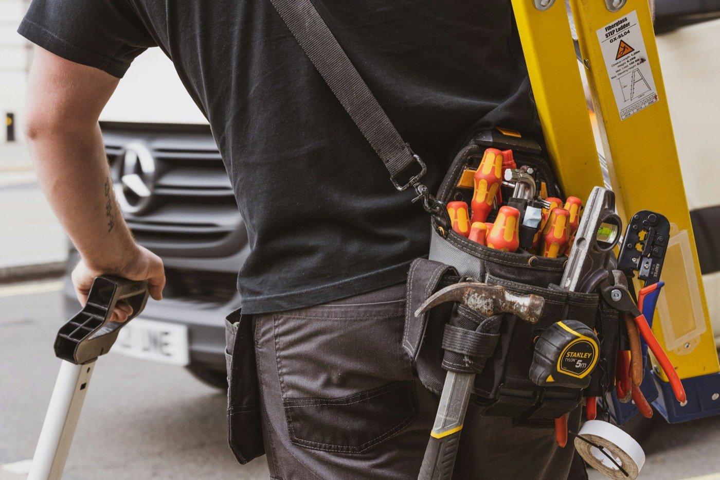 HVAC technician with tool belt and ladder heading to an emergency service call