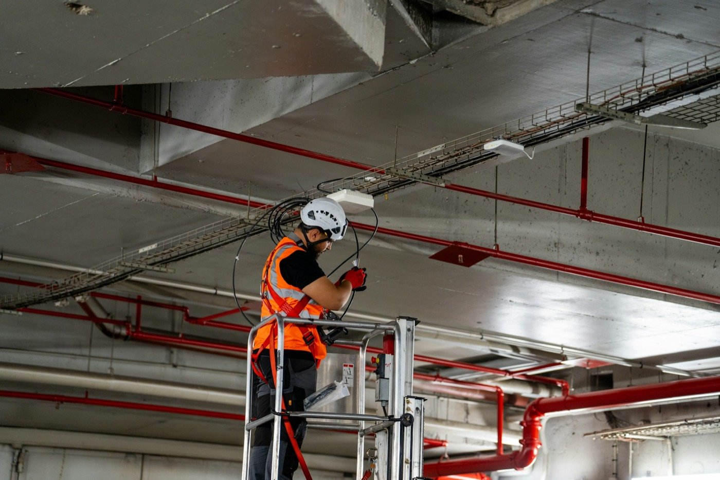 HVAC technician on a ladder servicing heating system lines