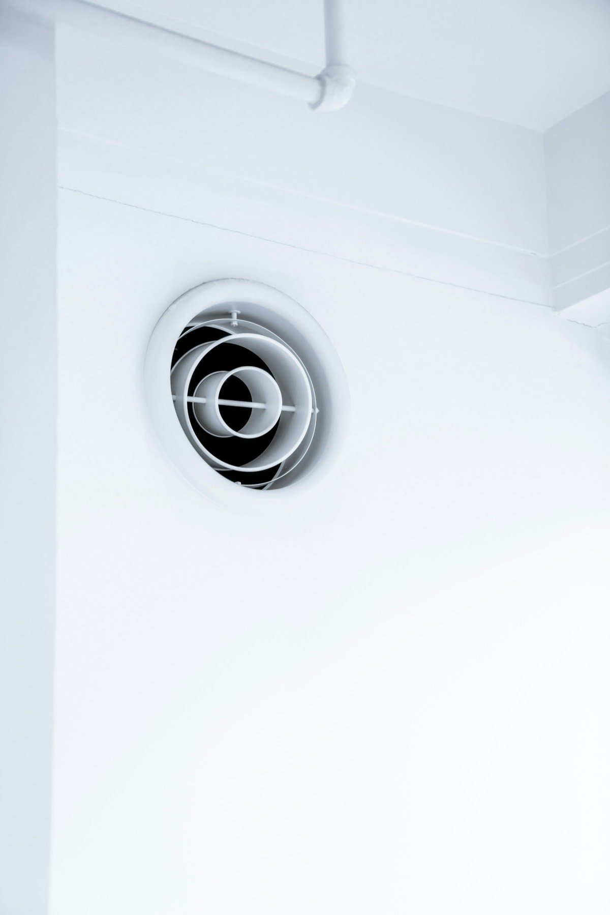 Clean round air vent on a white wall for improved indoor air quality